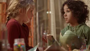 Een foto van Saïd en Anna die naar elkaar kijken. Saïd heeft een tube lijm vast. Met de tube lijm wil hij een lichtgroene vaas gaan lijmen die gebroken voor Saïd staat. De kapotte stukken van de vaas liggen links naast de vaas.