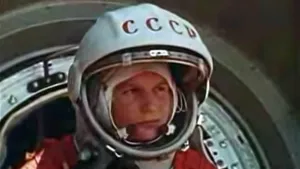 Een foto van de Russische astronaute Valentina Teresjkova in een ruimtepak met opengeklapte helm. Ze staat bij een ronde opening van de raket waarmee ze als eerste vrouw ooit de ruimte ingaat. Op de helm van Valentina staat CCCP.