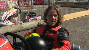 Een foto van presentator Pascal die op een kart zit. Hij houdt zijn helm vast in zijn handen. Op de achtergrond is de kartbaan te zien en er staat nog een lege kart.