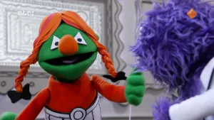 Een foto van een groene pop met rood gevlecht haar die aan het praten is met een paarse pop.