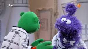 Een foto van een groene pop die met aan het praten is met een paarse pop in het museum van gewone dingen.