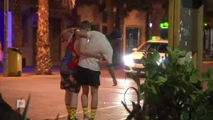 Twee mannen lopen over straat. De een houdt de andere vast omdat die dronken is.