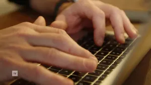 Een foto van twee handen die wat aan het typen zijn op het toetsenbord van een laptop.