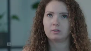 Een foto van een jonge vrouw die met haar gezicht recht voor de camera zit terwijl ze naar boven kijkt.