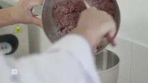 Een foto van iemand die kweekvlees in een pan doet uit een andere pan.