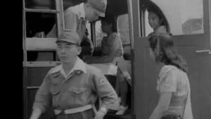 Een foto in zwart-wit van soldaten die uit een bus stappen. Er zitten een aantal vrouwen in de bus en er staat een vrouw aan de buitenkant voor de deur.