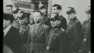 Een zwart-witfoto van een groepje van ongeveer tien mannen die allemaal dezelfde kant op kijken. De meeste hebben een uniform aan, maar sommige niet.
