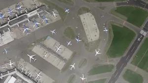 Een foto van luchthaven Schiphol van bovenaf gezien. Je ziet vliegtuigen en gebouwen.