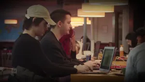 Een foto waar meerdere mensen aan een grote tafel op internet zitten met laptops.