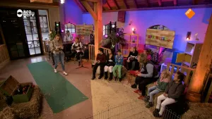 Foto van studioachtige ruimte waarin allemaal kinderen zitten en een vrouw loopt naar ze toe.
