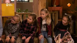 Foto van aantal kinderen die naast elkaar in een kamer zitten, ze kijken ergens naartoe, niet te zien wat.