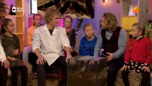 Foto van aantal kinderen die bij elkaar zitten, bij ze zitten ook twee mannen.