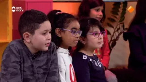 Foto van aantal kinderen die naast elkaar zitten, je ziet vooral hun hoofden, ze kijken ergens naartoe.