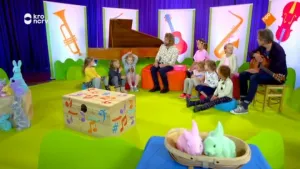 Foto van een studio waarin aantal kinderen bij elkaar zitten en twee mannen, allerlei paasversieringen eromheen.