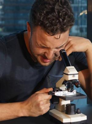 Ajouad el Miloudi kijkt door microscoop