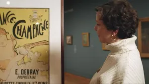 Een foto van Wieteke die in een museum naar een kunstwerk staat te kijken waarop een vrouw staat die een alcoholisch drankje aan het drinken is. Er staat heel groot France-Champagne op. Champagne is een alcoholische drank.