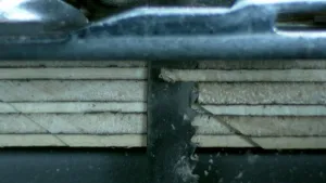 Een foto van het zaaggedeelte van een decoupeerzaag die stukjes van de zijkant van een houten plank afzaagd. 