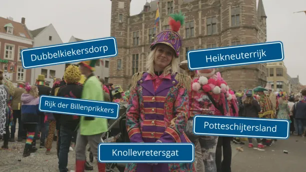 Een foto van Janouk in kleurige carnavalskleding. Er staan vijf straatnaamborden voor de foto, zo heten feestvierende plaatsen tijdens carnaval: "Dubbelkiekersdorp", "Heikneuterrijk", "Rijk der Billenprikkers", "Potteschijtersland" en "Knollevretersgat".
