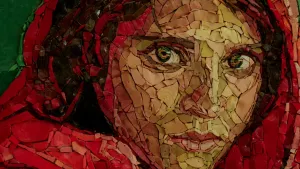 Een foto van een gekleurd mozaïek kunstwerk. Op het kunstwerk is het gezicht van een vrouw te zien met groene ogen. De vrouw draagt rode kleding en de kap van het kledingstuk bedekt het haar van de vrouw.