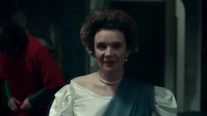 Een foto van een vrouw die verkleed is als Amalia van Solms. Ze heeft een witte jurk aan, een ketting met witte parels en een groene sjerp van stof over haar linkerschouder. Ook heeft ze oorbellen met witte parels in.