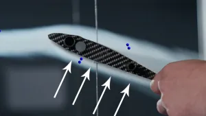 Een foto van de zijkant van een losse vliegtuigvleugel. Onder de vleugel zijn witte pijlen te zien, die naar de onderkant van de vleugel wijzen. Om de vleugel heen is een witte lucht te zien en daarbinnen blauwe puntjes, die luchtmoleculen uitbeelden.