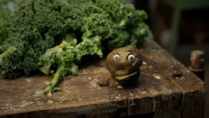 Een foto van een pratende aardappel met ogen die naast een hoop broccoli zit.