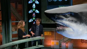 Een foto van een man en een vrouw in de Earth Challenge studio. Rechts is een kop van een met de computer gemaakte Haai zichtbaar.