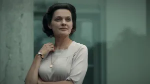 Een foto van een acteur die Juliana speelt, de dochter van Koningin Wilhelmina. Ze houdt met haar rechterhand haar halsketting vast.