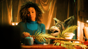 Een foto van ezel Chiel die tegen een vrouw praat. De vrouw heeft een stok in haar handen waar bladeren op zitten.