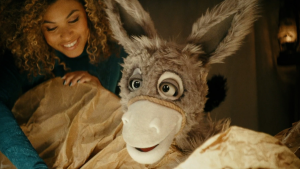 Een foto van ezel Chiel die ergens overheen kijkt. Er staat een vrouw naast hem die naar beneden kijkt.