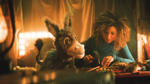 Een foto van ezel Chiel die naast een vrouw zit die met een hamer in haar hand wat op iets aan het timmeren is.