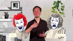 Een foto van een presentator met links naast de presentator een afbeelding van een vrolijk lachend masker met een rode pruik op en de tekst "Thalia" eronder. Rechts is een huilend masker met een zwarte pruik te zien en de tekst "Melpomene" eronder.