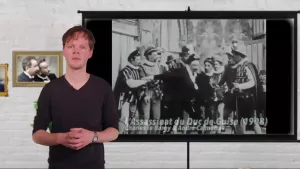 Een foto van een presentator met op de achtergrond een projectiescherm. Op het scherm is een stilstaand beeld uit een Franse film te zien van mannen in ouderwetse kleding. Onderaan de filmtitel: "L'assassinat du Duc de Guise" en het jaartal 1908.