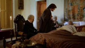 Een foto van een ernstig zieke man die in bed ligt. Op de dekens ligt een document, een aflaat genoemd. Naast het bed staat de predikant Maarten Luther met een gesloten boek in zijn handen en zitten een vrouw en een man op een stoel.