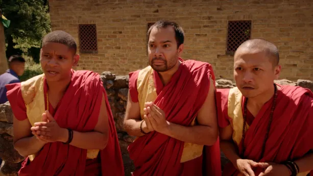 Een foto van drie Tibetaanse monniken in traditionele kleding, geel en rood en met een rode lap stof om de schouder. Iedere monnik staat op een boeddhistische manier met zijn eigen handen tegen elkaar op de foto.
