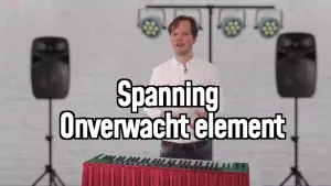 Een foto van een presentator met voor zich een elektrische piano. Voor de foto is de tekst "Spanning Onverwacht element" te lezen. Achter de presentator staan geluidsboxen en hangen lampen die gebruikt worden om licht op een podium te kunnen schijnen.