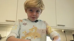 Een foto van een jongen die in de keuken eten aan het bereiden is.