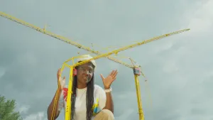 Een foto van presentator Tirsa die achter twee kleine versies van kranen zit.