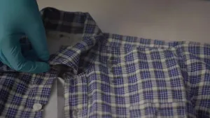 Een foto van de bovenkant van de blouse van het Joodse jongetje Bertie, waar vlekken op te zien zijn. De blouse heeft een patroon met blauwe, grijze, zwarte en smalle witte strepen.