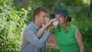 Een foto van presentatoren Jurre en Emma die armen met elkaar gekruist hebben en tegelijk een glas melk drinken.