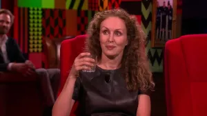 Een foto van een vrouw die in de studio zit van Eus' Boekenclub. Op de achtergrond zit er man van het publiek.