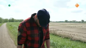 Een foto van presentator Tim die buiten op een pad loopt naast een weiland. Hij kijkt naar beneden.