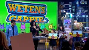 Een foto van presentator Sahil en wetensgappie Cynthia Liem in de studio. Naast hen staan drie kinderen die ieder een foto van een paard tonen aan het publiek. 