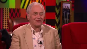 Een foto van een man die op een rode stoel in de studio zit van Eus’ Boekenclub.