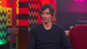 Een foto van een man die op een rode stoel zit in de studio van Eus’ Boekenclub.