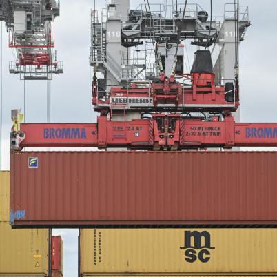 Rode container in de lucht vervoerd door grote grijparm