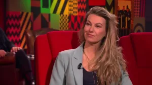 Een foto van een vrouw die op een rode stoel in de studio zit.