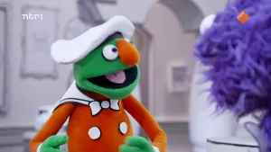 Een foto van een groene pop die met een paarse pop praat die op de voorgrond staat.