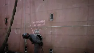 Een foto van iemand die het schip repareert en uit een gat in de zijkant van het schip klimt.