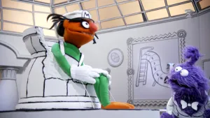 Een foto van een oranje pop die in een kapotte pot zit in het museum van gewone dingen. Er kijkt een paarse pop naar de oranje pop in de pot.